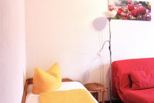 a living room with a red couch and a lamp at Pension An der Kamske, FZ 5 Familien in Lübbenau