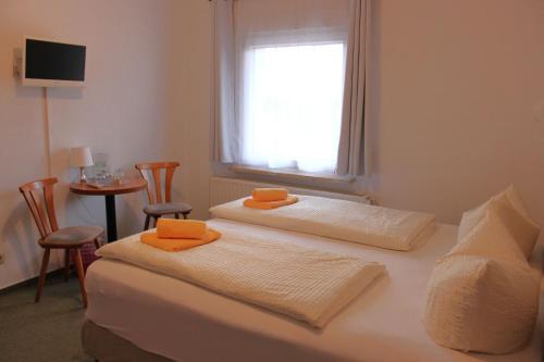 um quarto com duas camas com toalhas cor de laranja em Pension An der Kamske, FZ 5 Familien em Lübbenau