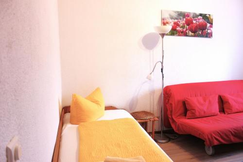 Habitación pequeña con cama y sofá rojo. en Pension An der Kamske, FZ 5 Familien, en Lübbenau