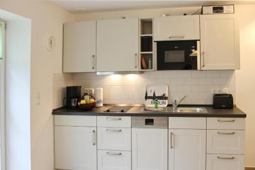 a kitchen with white cabinets and a sink at Hopkas Remise in Lehde