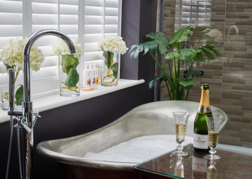 Boutique Bedrooms في ثورنهام: حمام مع حوض مع زجاجة من الشمبانيا