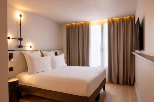 a hotel room with a white bed and a window at Hôtel Esté in Paris