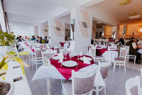 a dining room with white tables and white chairs at Hotel Tusnad in Băile Tuşnad