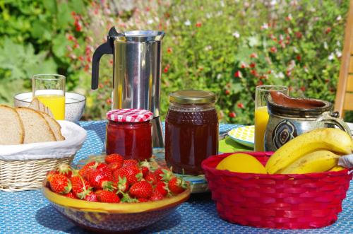 - une table avec des fruits, de la confiture et un panier de pain dans l'établissement LES CHAMBRES AUX LOUPS, à Iffendic