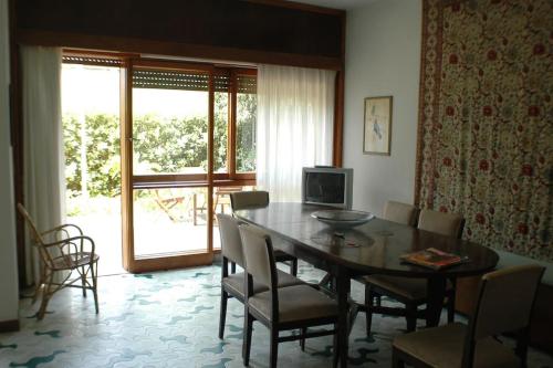 ein Esszimmer mit einem Tisch, Stühlen und einem TV in der Unterkunft Villa Il Platano con giardino Beachfront in Forte dei Marmi
