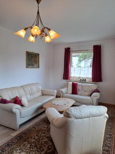 a living room with white furniture and a chandelier at Keller´s Ferienwohnung an der Saale in Schwarzenbach an der Saale