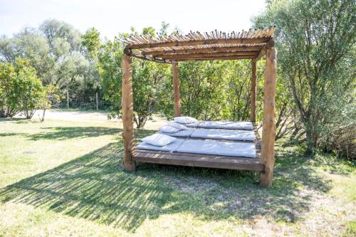 a bed with a wooden canopy in a field at Agriturismo Sa Mendhula in Cugnana