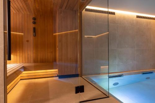 a sauna with a glass shower and a tub at Hôtel Esté in Paris