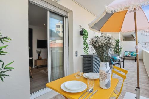 une table jaune avec un vase de fleurs et un parasol dans l'établissement Studio Nocturnelle - Welkeys, à Antibes