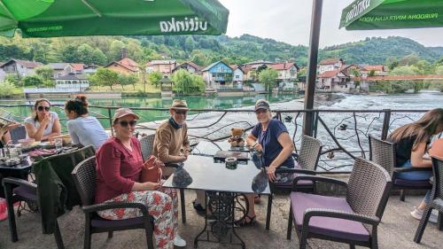 a group of people sitting at a table with a dog at Haus Viktoria near Banja Luka in Banja Luka