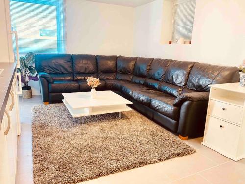 a brown leather couch in a living room with a coffee table at Lovely 3-bed Flat In Stockholm in Sollentuna