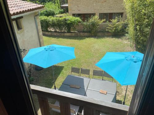 a balcony with two blue umbrellas and a table and chairs at Domaine Les Maurelles in Milhac