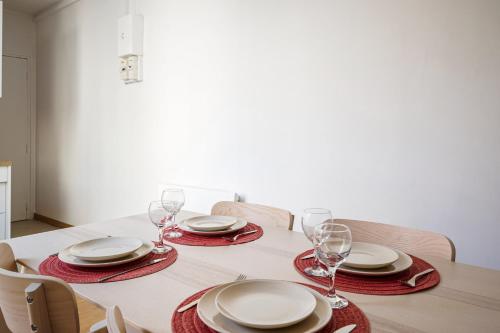 une table à manger avec des assiettes et des verres rouges et blancs dans l'établissement Appartement Amavel - Welkeys, à Paris