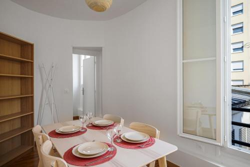 een witte eetkamer met een tafel en stoelen bij Nice flat in the 11th district of Paris - Welkeys in Parijs