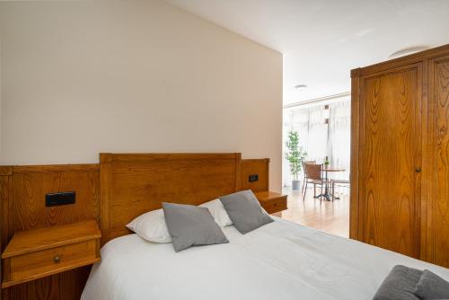 1 dormitorio con cama blanca y cabecero de madera en MyHouseSpain - Buen Suceso Apartments, en Gijón