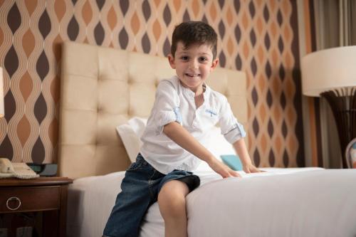 a young boy sitting on top of a bed at Hilton Porto Alegre, Brazil in Porto Alegre