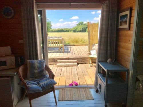une porte ouverte s'ouvrant sur une terrasse avec une chaise et un banc. dans l'établissement The Log Cabin, à Wimborne Minster