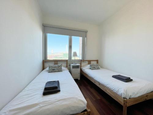 two twin beds in a room with a window at Forum Playa and Pool Barcelona in Barcelona