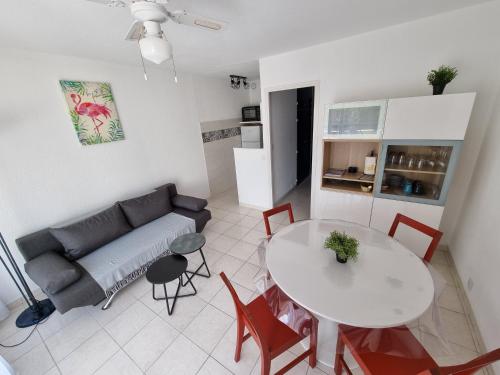 a living room with a couch and a table at En bord de mer, avec Grande terrasse et Climatisation in Le Grau-du-Roi