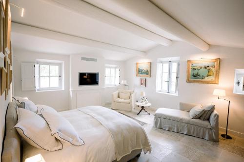 a white bedroom with a large bed and a couch at Le Domaine du Fortin in Ménerbes