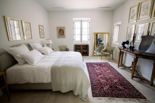 ein Schlafzimmer mit einem großen weißen Bett und einem roten Teppich in der Unterkunft Le Domaine du Fortin in Ménerbes