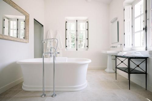 a white bathroom with a tub and two sinks at Le Domaine du Fortin in Ménerbes