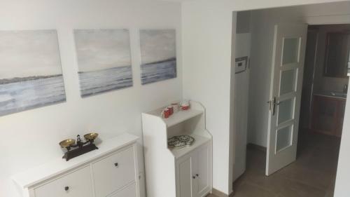 um quarto branco com três pinturas na parede em El Molino 1 em Muros de Nalón