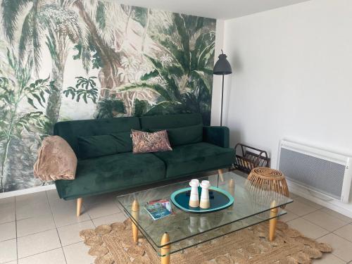 uma sala de estar com um sofá verde e uma mesa em Beldi, Bel appartement dans un environnement calme em Montgermont
