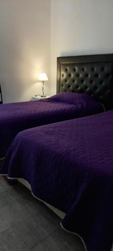 a bedroom with a purple bed with a lamp on a table at LA ESPERANZA in City Bell