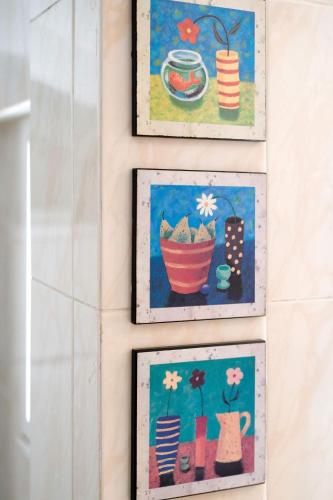 three paintings of flowers and pots on a wall at Buen Camino Arzua in Arzúa