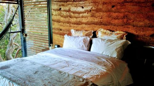 Bett mit Kissen in einem Zimmer mit Ziegelwand in der Unterkunft Casa da Serra in Cavalcante