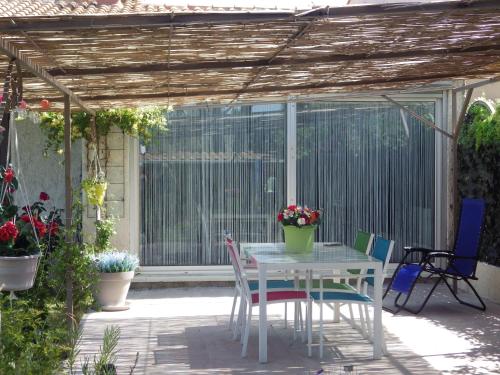 une table et des chaises sous une pergola sur une terrasse dans l'établissement Chez Noêlle, à LʼIsle-sur-la-Sorgue