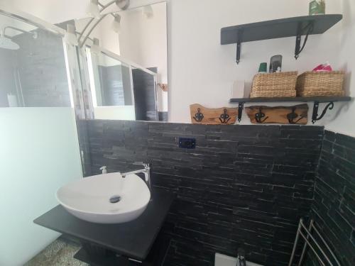 ein Bad mit einem schwarzen und weißen Waschbecken und einem Spiegel in der Unterkunft Vista Mare Portofino by PortofinoVacanze in Gravero