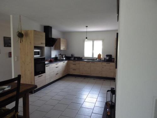 une cuisine avec des armoires en bois et un sol carrelé dans l'établissement Chez Noêlle, à LʼIsle-sur-la-Sorgue