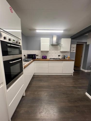 uma cozinha com armários brancos e um forno com placa de fogão em Hartington House em Middlesbrough