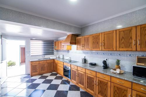 a kitchen with wooden cabinets and a checkered floor at Casa Xadrez in Povoação