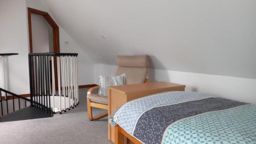 a bedroom with a bed and a chair in it at North End The Cottage in Nairn