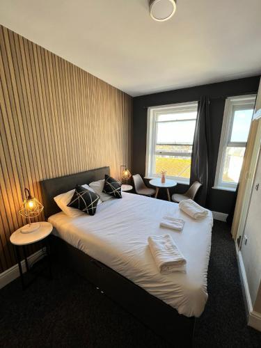 a bedroom with a bed with two tables and two windows at OYO Marine Parade Hotel, Eastbourne Pier in Eastbourne