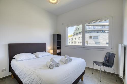 - une chambre avec un grand lit blanc, une chaise et une fenêtre dans l'établissement View point Les tresums - OG IMMO, à Annecy