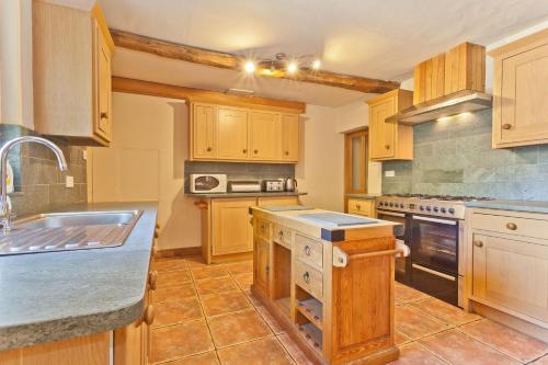 a large kitchen with wooden cabinets and a sink at Bridge Cottages, Bridge House & Bridge Suite, Sleeps 12 in Coniston
