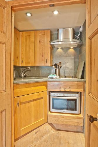 a kitchen with wooden cabinets and a sink and a microwave at Bridge Cottages, Bridge House & Bridge Suite, Sleeps 12 in Coniston