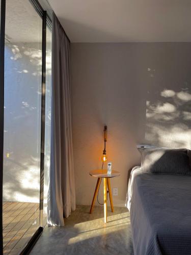 a bedroom with a bed and a table next to a window at Statera Host in Alto Paraíso de Goiás