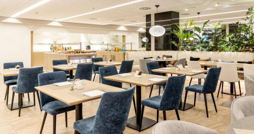 a restaurant with wooden tables and blue chairs at Ilunion Barcelona in Barcelona