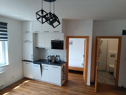eine Küche mit weißen Schränken und einer schwarzen Arbeitsplatte in der Unterkunft Blues Rooms in Gdynia
