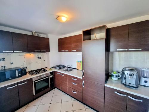 een keuken met houten kasten en een fornuis met oven bij RING - DeLuxe Spacious Apartment, Big Terrace, Plus Parking in Timişoara