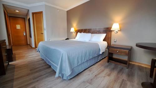 a hotel room with a large bed and a table at Hotel Diego de Almagro Coyhaique in Coihaique