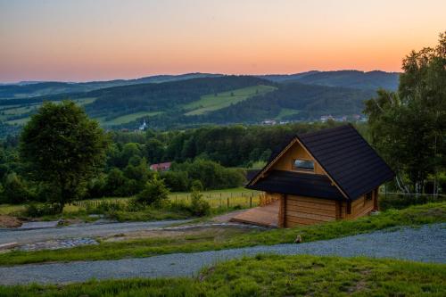 una cabaña en una colina con una puesta de sol en el fondo en Domek Muflon w Górach Sowich, en Jugów