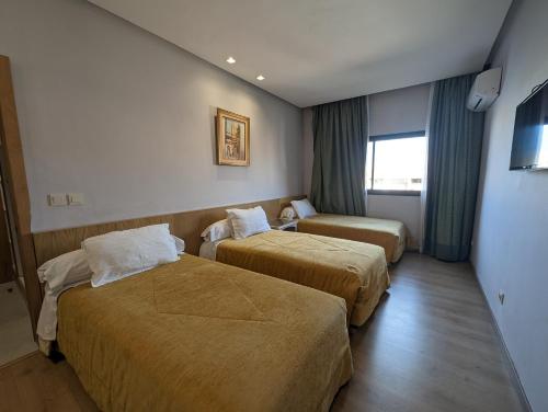 a hotel room with two beds and a window at Sahara Line Hotel in Laayoune