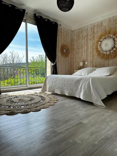 une chambre avec un grand lit et une grande fenêtre dans l'établissement Maison de L'Aube, à Villes-sur-Auzon