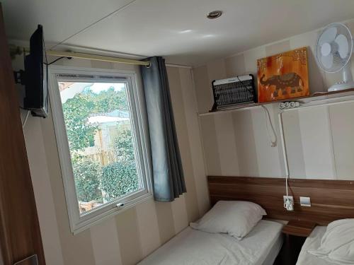 a small room with a bed and a window at MOBIL HOME LMNP GUIGON in La Roque-dʼAnthéron